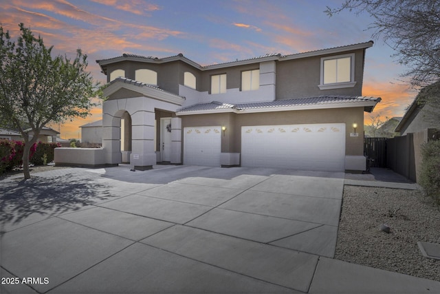 view of front of house featuring stucco siding, fence, concrete driveway, an attached garage, and a tiled roof