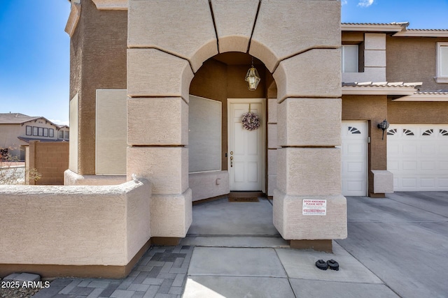 doorway to property with a tiled roof, stucco siding, and an attached garage