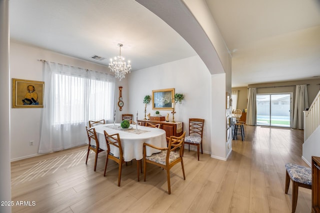 dining space featuring light wood finished floors, visible vents, a healthy amount of sunlight, and arched walkways