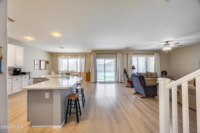 kitchen featuring a wealth of natural light, white cabinets, light wood-type flooring, and a kitchen bar