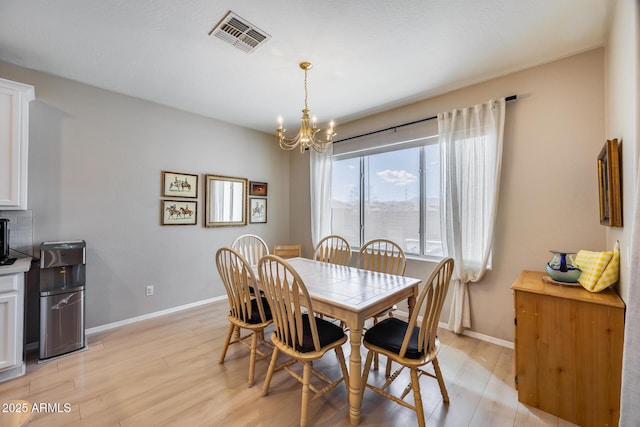 dining room with a notable chandelier, visible vents, light wood-type flooring, and baseboards