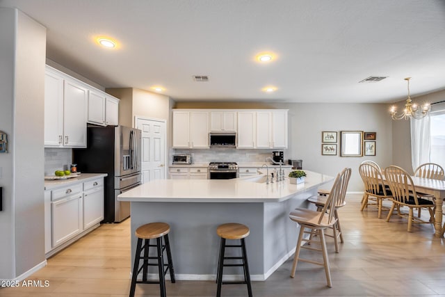 kitchen featuring white cabinetry, appliances with stainless steel finishes, a breakfast bar, and light countertops