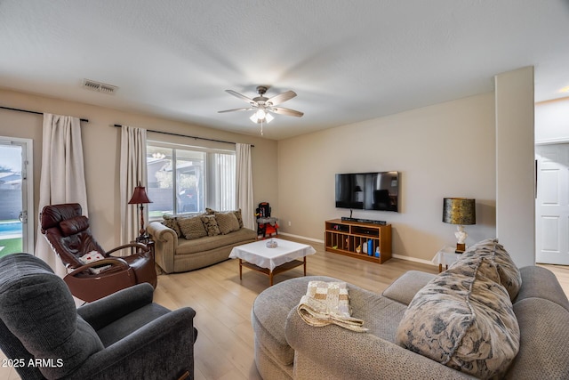 living room featuring a ceiling fan, wood finished floors, visible vents, and baseboards