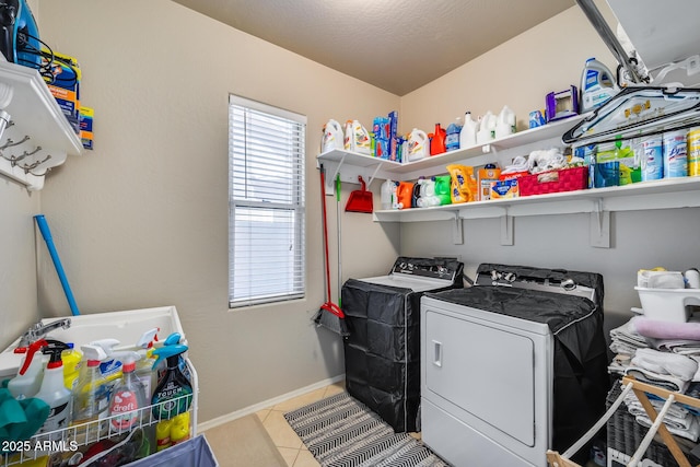 laundry area with light tile patterned floors, baseboards, washing machine and dryer, and laundry area