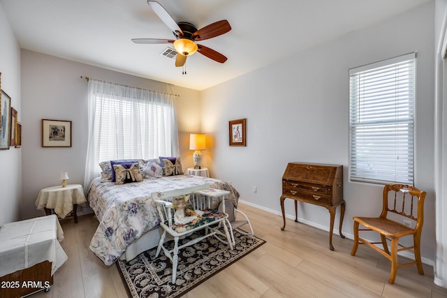 bedroom with a ceiling fan, light wood-style floors, visible vents, and baseboards