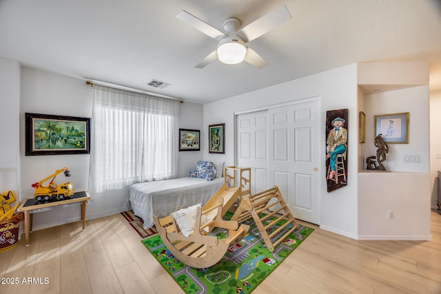 bedroom featuring visible vents, a ceiling fan, wood finished floors, a closet, and baseboards