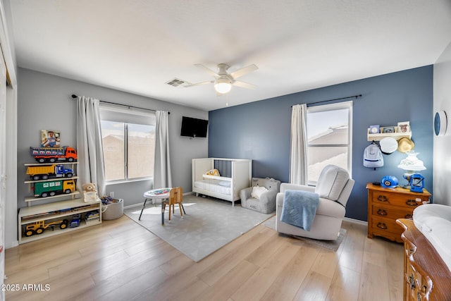 living area featuring visible vents, baseboards, ceiling fan, and wood finished floors