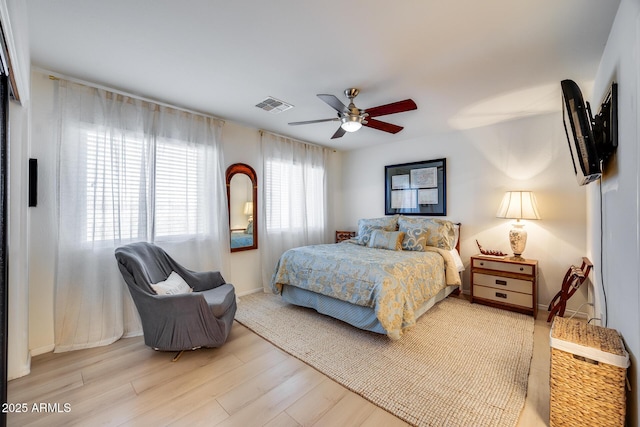 bedroom featuring visible vents, baseboards, light wood-style floors, and a ceiling fan