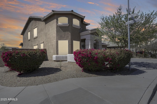 view of side of home with a tiled roof and stucco siding