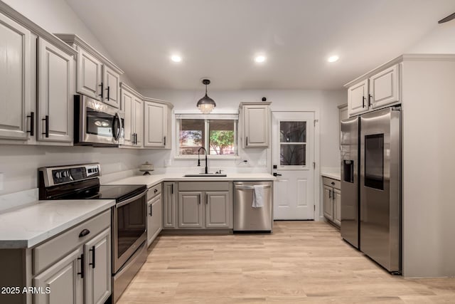 kitchen featuring sink, stainless steel appliances, light hardwood / wood-style flooring, decorative light fixtures, and gray cabinets