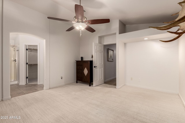 unfurnished bedroom featuring a closet, a spacious closet, ceiling fan, and light colored carpet