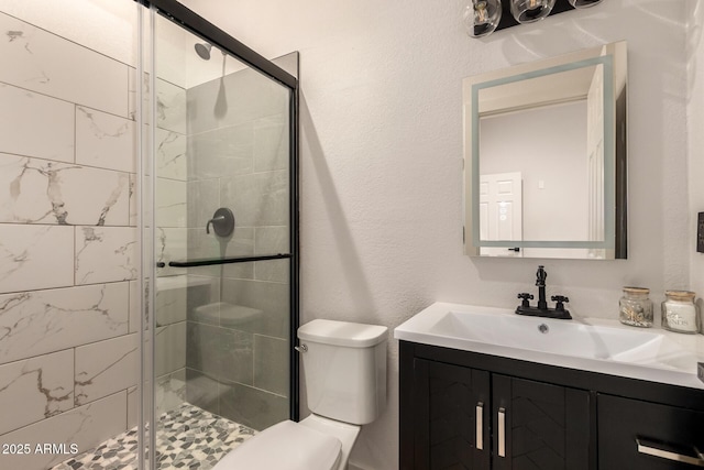 bathroom featuring vanity, toilet, and a shower with door