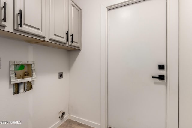 laundry room with electric dryer hookup, hookup for a washing machine, hardwood / wood-style floors, and cabinets