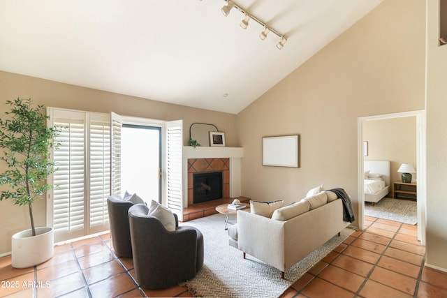 tiled living room featuring a tile fireplace, rail lighting, and high vaulted ceiling