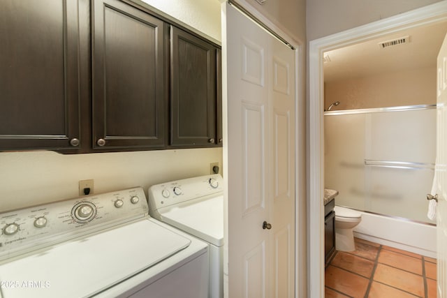 laundry room featuring washer and clothes dryer, cabinets, and light tile patterned flooring