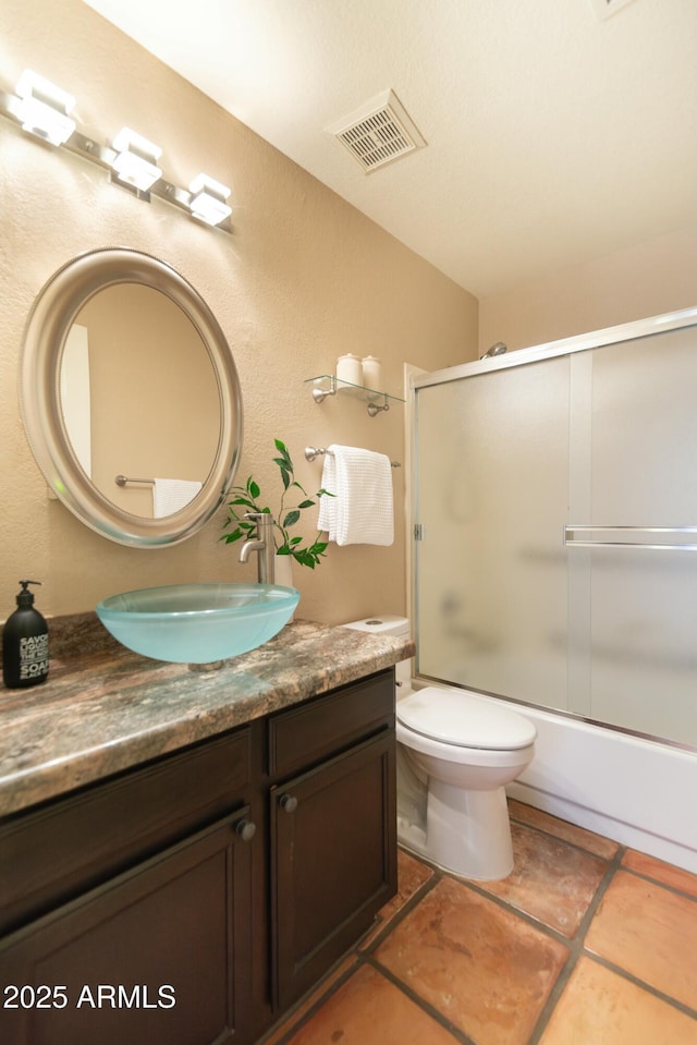 full bathroom featuring toilet, vanity, and bath / shower combo with glass door