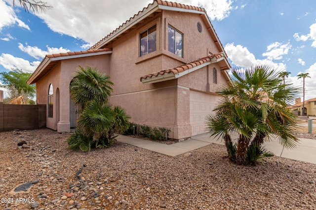 view of front of house with concrete driveway, stucco siding, fence, an attached garage, and a tiled roof