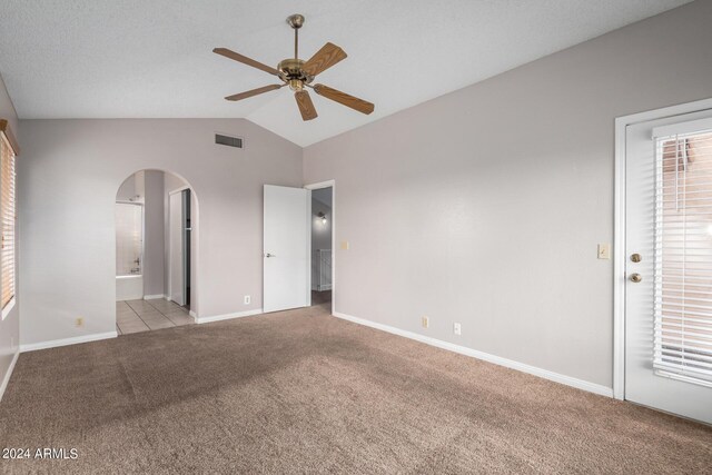 interior space featuring connected bathroom, vaulted ceiling, light carpet, and ceiling fan