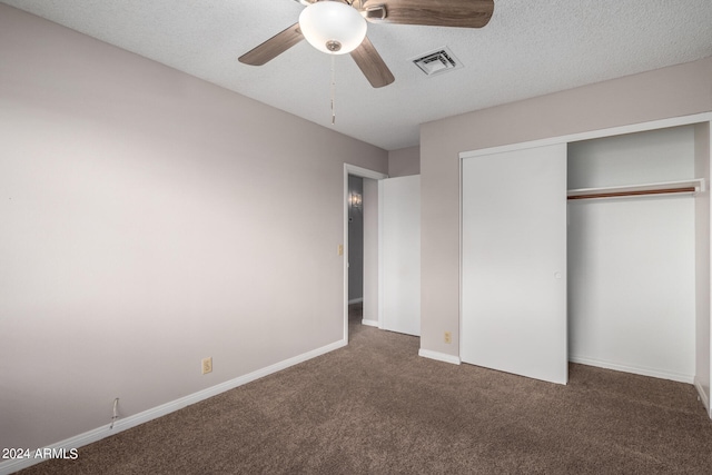 unfurnished bedroom featuring ceiling fan, a textured ceiling, a closet, and dark colored carpet