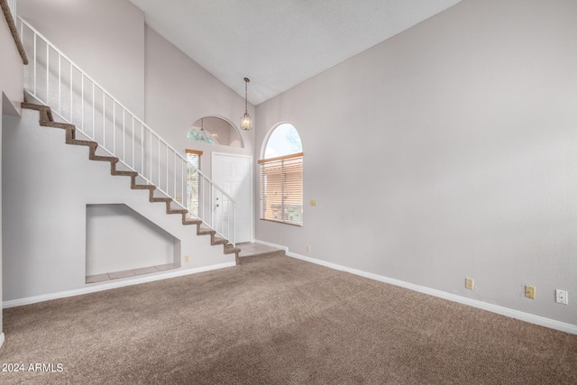 interior space featuring high vaulted ceiling, baseboards, and stairs