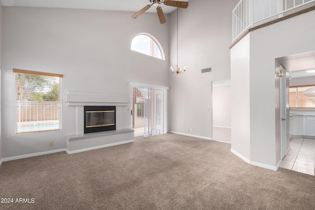 unfurnished living room featuring a glass covered fireplace, ceiling fan with notable chandelier, light colored carpet, and visible vents