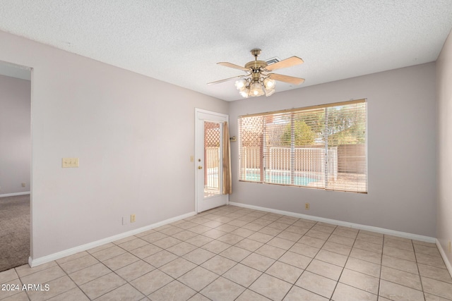 empty room with baseboards, ceiling fan, and a textured ceiling