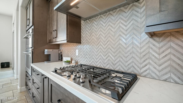122 E Desert Wind Dr, Phoenix, AZ 85048 - kitchen with tasteful backsplash, custom range hood, light stone countertops, stone tile flooring, and stainless steel gas cooktop