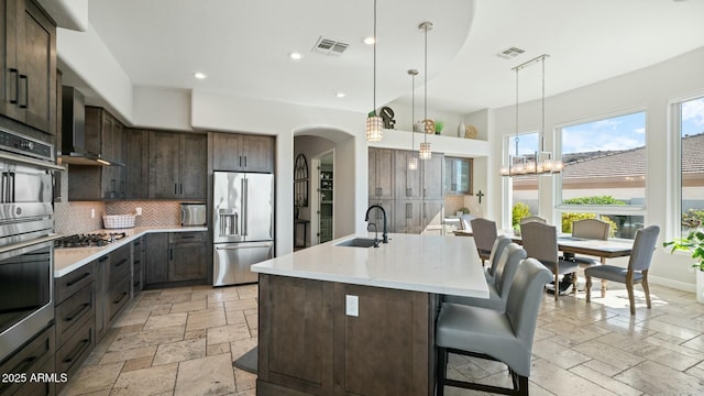 122 E Desert Wind Dr, Phoenix, AZ 85048 - kitchen featuring visible vents, wall chimney exhaust hood, appliances with stainless steel finishes, stone tile flooring, and a sink