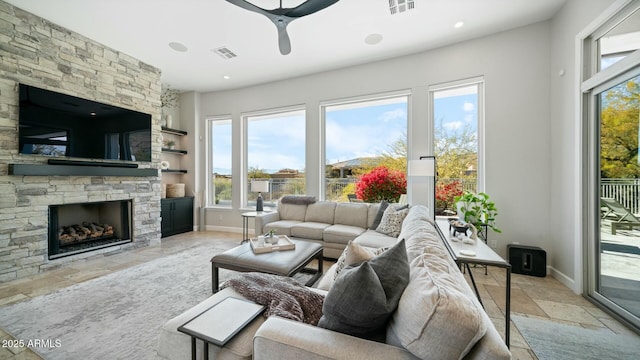 122 E Desert Wind Dr, Phoenix, AZ 85048 - living area with baseboards, visible vents, ceiling fan, stone tile flooring, and a fireplace