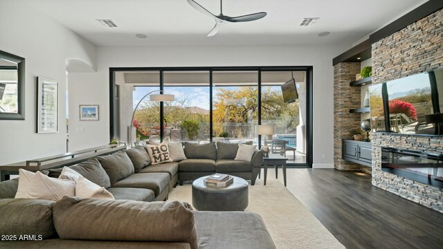 122 E Desert Wind Dr, Phoenix, AZ 85048 - living area featuring dark wood-type flooring, visible vents, a stone fireplace, and a ceiling fan