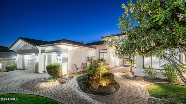 view of front of home featuring a garage, decorative driveway, and stucco siding