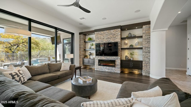 122 E Desert Wind Dr, Phoenix, AZ 85048 - living room featuring built in shelves, a stone fireplace, a ceiling fan, visible vents, and baseboards