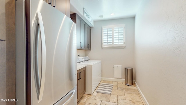 122 E Desert Wind Dr, Phoenix, AZ 85048 - laundry room featuring cabinet space, stone tile floors, baseboards, and washer and clothes dryer