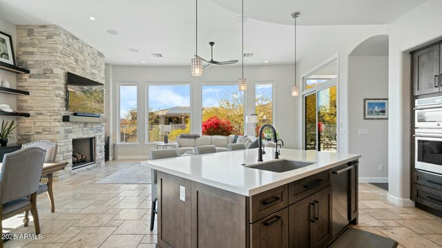 122 E Desert Wind Dr, Phoenix, AZ 85048 - kitchen featuring stone tile floors, a fireplace, a sink, open floor plan, and light countertops