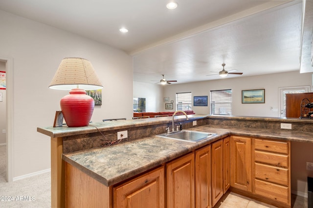 kitchen with kitchen peninsula, ceiling fan, sink, and light carpet