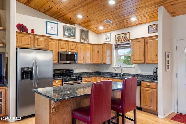 kitchen with a kitchen breakfast bar, stainless steel appliances, light hardwood / wood-style flooring, a kitchen island, and lofted ceiling