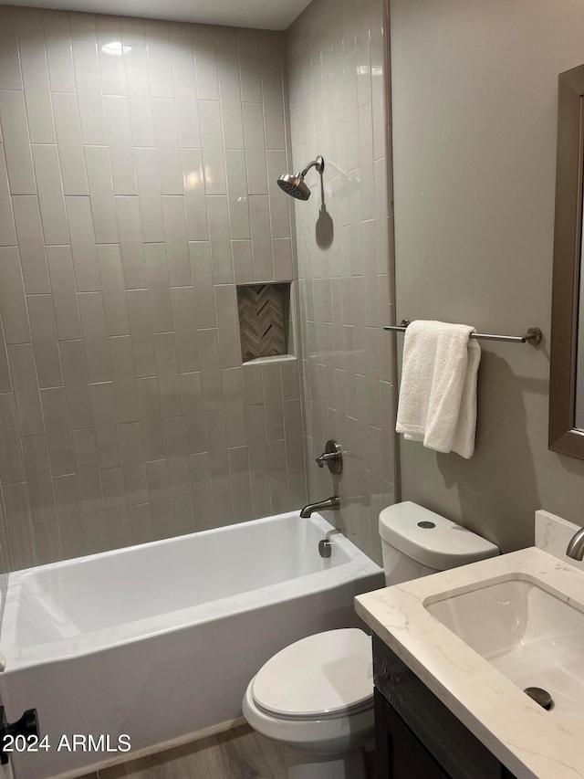 full bathroom featuring tiled shower / bath, hardwood / wood-style floors, vanity, and toilet