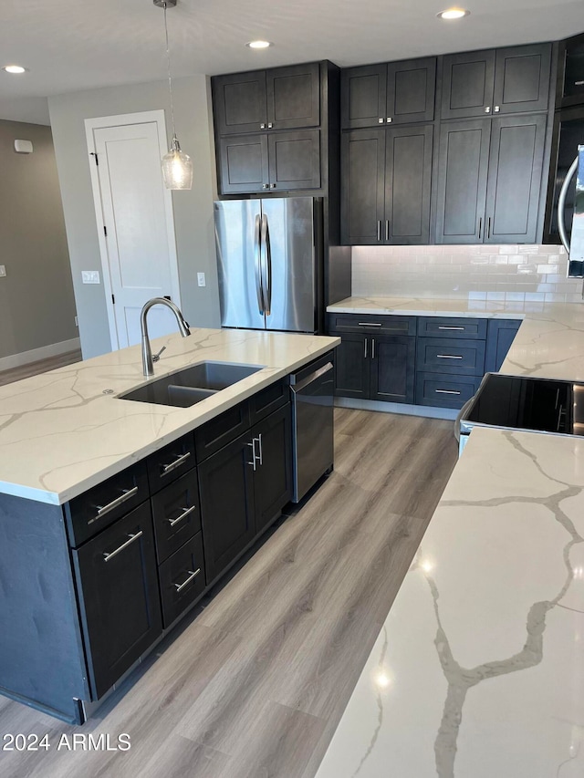 kitchen with sink, light hardwood / wood-style flooring, light stone countertops, decorative light fixtures, and stainless steel appliances