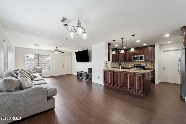 living room with dark hardwood / wood-style flooring and ceiling fan with notable chandelier