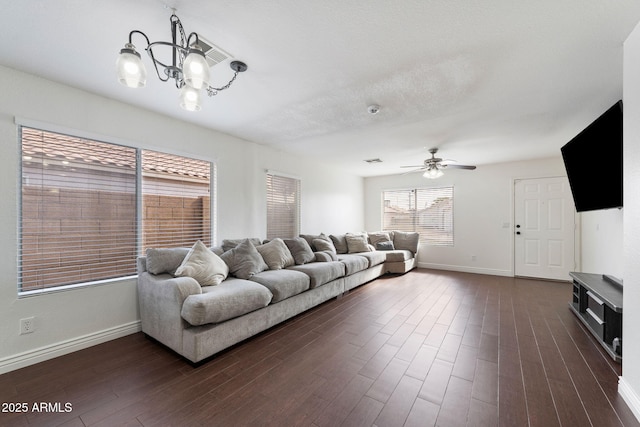 living room featuring ceiling fan with notable chandelier, a textured ceiling, and dark hardwood / wood-style flooring