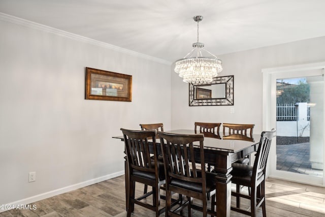 dining area with hardwood / wood-style floors, an inviting chandelier, and ornamental molding