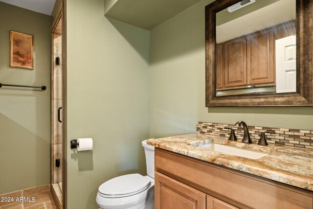 bathroom featuring an enclosed shower, vanity, toilet, and tasteful backsplash