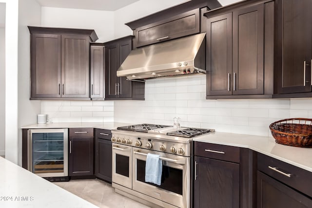 kitchen featuring beverage cooler, tasteful backsplash, range with two ovens, light tile floors, and wall chimney range hood