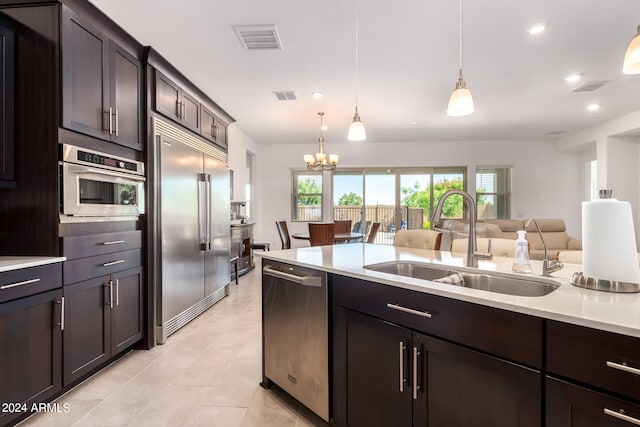 kitchen with stainless steel appliances, dark brown cabinetry, pendant lighting, sink, and light tile flooring