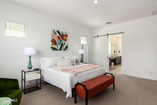 carpeted bedroom with a barn door and ensuite bathroom