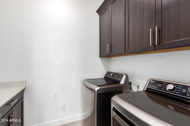 washroom with cabinets, washing machine and dryer, and light wood-type flooring