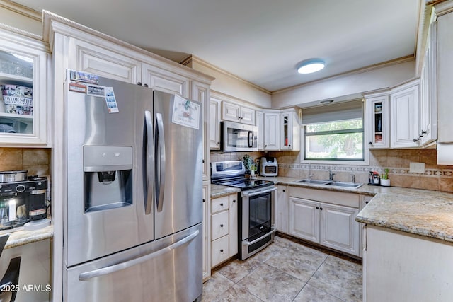6721 E Mcdowell Rd Unit B309, Scottsdale, AZ 85257 - kitchen featuring appliances with stainless steel finishes, decorative backsplash, glass insert cabinets, light stone counters, and crown molding