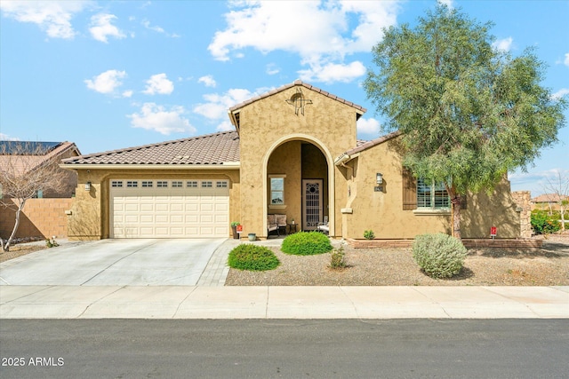 mediterranean / spanish-style home featuring stucco siding, driveway, fence, an attached garage, and a tiled roof