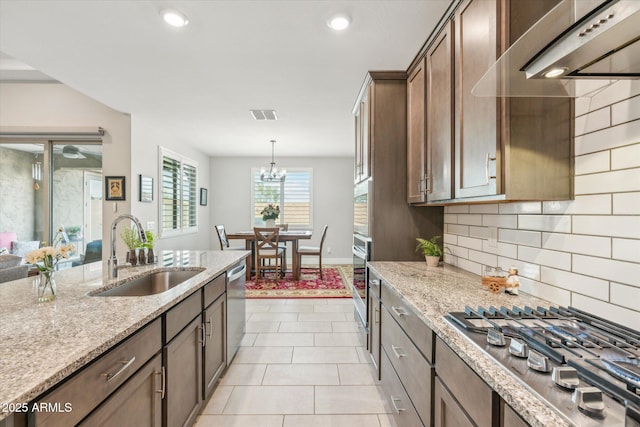 kitchen featuring visible vents, backsplash, exhaust hood, stainless steel appliances, and a sink