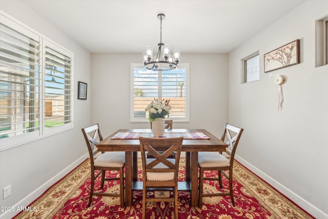 dining space featuring wood finished floors, baseboards, and a chandelier